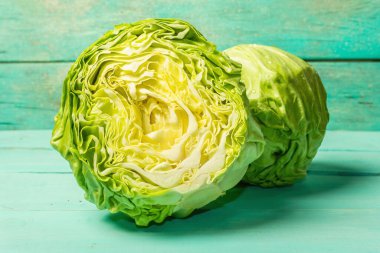 Taze taze lahana, parlak yeşil arka planda yarısı ve tamamı. Modern sert ışık, karanlık gölge. Bahar salatası kesmek için sebzeler. Vejetaryen yemeği, diyet, vitamin