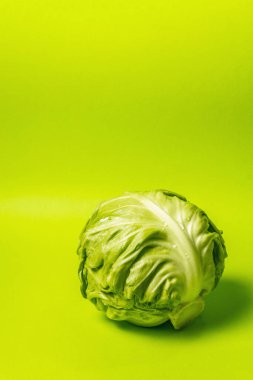 Taze taze lahana, parlak yeşil arka planda koca bir kafa. Modern sert ışık, karanlık gölge. Bahar salatası kesmek için sebzeler. Vejetaryen yemeği, diyet, vitamin