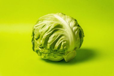 Taze taze lahana, parlak yeşil arka planda koca bir kafa. Modern sert ışık, karanlık gölge. Bahar salatası kesmek için sebzeler. Vejetaryen yemeği, diyet, vitamin