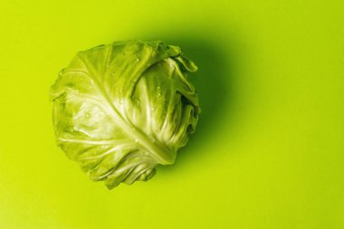 Taze taze lahana, parlak yeşil arka planda koca bir kafa. Modern sert ışık, karanlık gölge. Bahar salatası kesmek için sebzeler. Vejetaryen yemeği, diyet, vitamin