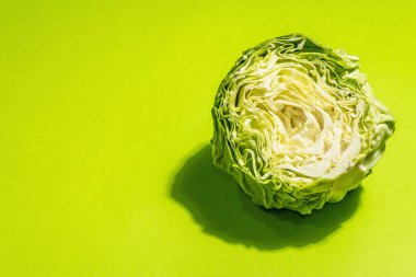 Taze taze lahana, parlak yeşil arka planda yarım kafa. Modern sert ışık, karanlık gölge. Bahar salatası kesmek için sebzeler. Vejetaryen yemeği, diyet, vitamin