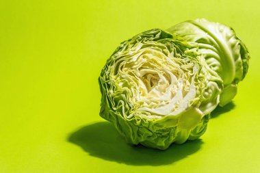 Taze taze lahana, parlak yeşil arka planda yarısı ve tamamı. Modern sert ışık, karanlık gölge. Bahar salatası kesmek için sebzeler. Vejetaryen yemeği, diyet, vitamin