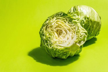 Taze taze lahana, parlak yeşil arka planda yarısı ve tamamı. Modern sert ışık, karanlık gölge. Bahar salatası kesmek için sebzeler. Vejetaryen yemeği, diyet, vitamin