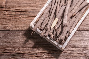 Çiğ Scorzonera ya da İspanyol tuzunu bir sandıkta. Modern sebzeler, sağlıklı yiyecekler, şeker hastaları için uygun. Modaya uygun sert bir ışık, karanlık bir gölge, ahşap masa, üst manzara.