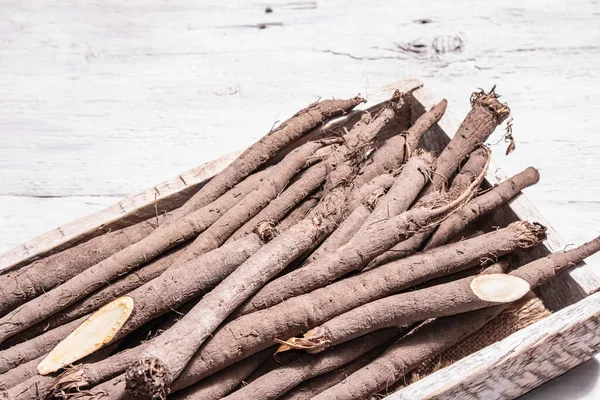 Bunch of raw Scorzonera or Spanish salsify. Modern vegetables, healthy food, suitable for diabetics. A trendy hard light, dark shadow, wooden background, copy space