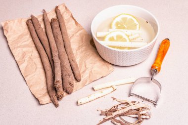 Çiğ Scorzonera ya da İspanyol tuzlusu. Yemek pişirme süreci. Deriyi soy ve soğuk suya limonla koy. Modern sebzeler, sağlıklı yiyecekler, şeker hastaları için uygun. Taş arkaplan, kopyalama alanı