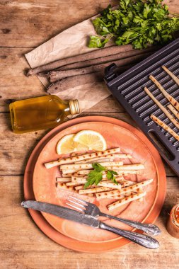 Soslu ızgara akrep. Çatal bıçak takımı, kırsal seramik tabaklar, ızgara, baharatlar. Eski ahşap masa, üst manzara.