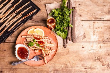 Soslu ızgara akrep. Çatal bıçak takımı, kırsal seramik tabaklar, ızgara, baharatlar. Eski ahşap masa, üst manzara.