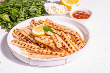 Soslu ızgara akrep çorbası. Modern sert ışık, karanlık gölge. Seramik standı, baharatlar, moda peçetesi. Beyaz alçı arka plan, kapat