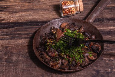 Eski bir dökme demir tavada kızarmış kraliyet şampiyonları. Modaya uygun sert ışık, karanlık gölge. Antika ahşap masa, kırsal gıda tarzı konsept, kopyalama alanı