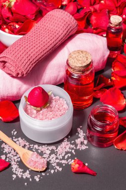 Taze gül yapraklı doğal spa konsepti. Gül tuzu, temel yağ, yumuşak havlular. Modern sert ışık, karanlık gölge. Siyah taş arkaplan, boşluğu kopyala