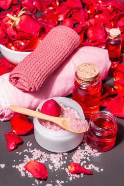 Taze gül yapraklı doğal spa konsepti. Gül tuzu, temel yağ, yumuşak havlular. Modern sert ışık, karanlık gölge. Siyah taş arkaplan, boşluğu kopyala