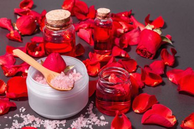 Taze gül yapraklı doğal spa konsepti. Gül tuzu, temel yağ, yumuşak havlular. Modern sert ışık, karanlık gölge. Siyah taş arkaplan, boşluğu kopyala