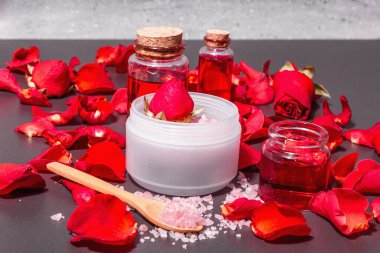 Taze gül yapraklı doğal spa konsepti. Gül tuzu, temel yağ, yumuşak havlular. Modern sert ışık, karanlık gölge. Siyah taş arkaplan, boşluğu kopyala