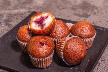 Kurabiyeler frenk üzümü reçeli doldurdu. Modern sert ışık, karanlık gölge. Seramik standı, taş beton zemin, kopyalama alanı