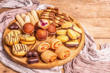 Çeşitli kurabiyeler ve kekler. Eski tahta tabağın üzerine ahşap kombinasyon tabağı, kapat.