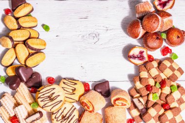 Çeşitli kurabiyeler ve kekler. Modaya uygun sert ışık, karanlık gölge. Beyaz tahta tahta arka plan, üst görünüm