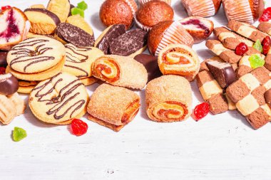 Çeşitli kurabiyeler ve kekler. Modaya uygun sert ışık, karanlık gölge. Beyaz tahta tahta arka plan, boşluğu kopyala