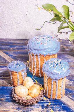 Mavi kremalı, üzeri yenebilir boncuklu Paskalya pastası. Doğal sağlıklı malzemeler, yuvadaki altın yumurtalar, şenlikli bir dekor. Modern stantlar, eski ahşap masa arkaplanı, kopyalama alanı