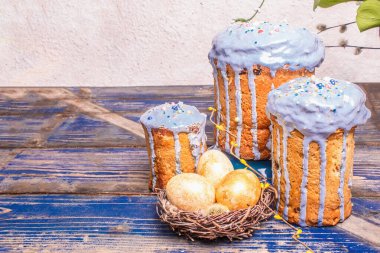 Mavi kremalı, üzeri yenebilir boncuklu Paskalya pastası. Doğal sağlıklı malzemeler, yuvadaki altın yumurtalar, şenlikli bir dekor. Modern stantlar, eski ahşap masa arkaplanı, kopyalama alanı