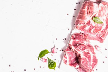 Çiğ domuz eti, dilimlenmiş et. Taze et, kuru sumak, sarımsak ve fesleğen yaprağı. Sağlıklı yemek pişirme konsepti, modaya uygun sert ışık, karanlık gölge. Beyaz macun arkaplan, üst görünüm