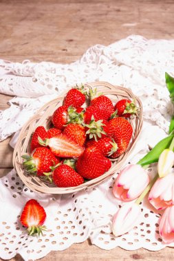Hasır tabakta olgun çilekler. Taze böğürtlen, aromatik nane, pembe laleler. Eski ahşap masa, eski örülmüş peçete, kırsal stil, kopyalama alanı