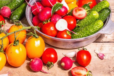 Yemek, hasat, yaz konsepti. Olgun organik çiftçi, kırmızı ve sarı domates, salatalık, turp, sarımsak ve taze fesleğen yaprağı çeşitleri. Eski ahşap masa, metin için yer