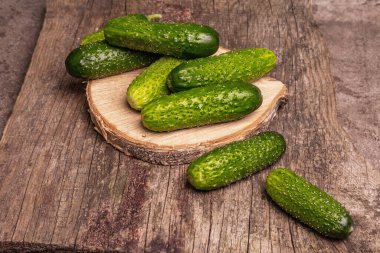 Tahta tezgahta gevrek salatalıklar. Taze yeşil sebzeler, organik çiftçi ürünü. Tahta doğrama tahtası, mermer taş zemin, kopyalama alanı