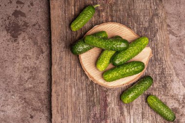 Tahta tezgahta gevrek salatalıklar. Taze yeşil sebzeler, organik çiftçi ürünü. Tahta doğrama tahtası, mermer taş arka plan, üst manzara.