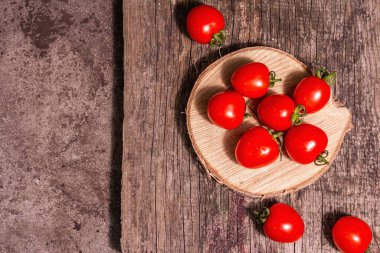 Ahşap tezgahta kırmızı kiraz domatesleri. Taze tatlı sebzeler, organik çiftçi ürünü. Modern sert ışık, karanlık gölge, doğrama tahtası, mermer taş zemin, üst görünüm