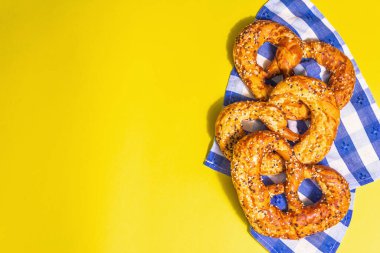 Oktoberfest konsepti: Geleneksel peçetede krakerler. Modaya uygun sert ışık, karanlık gölge. Pastel sarı arkaplan, üst görünüm