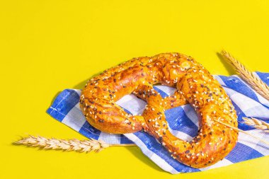 Oktoberfest konsepti: Geleneksel peçetede krakerler. Modaya uygun sert ışık, karanlık gölge. Kuru dikenler, pastel sarı arkaplan, metin için yer