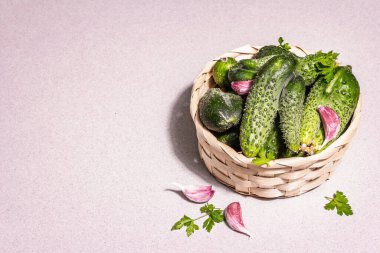 Sepetteki son moda çirkin organik salatalıklar. Taze sebzeler, sarımsak karanfilleri, maydanoz yeşillikleri. Çirkin yemek pişirme konsepti, modern sert ışık, karanlık gölge. Taş beton arkaplan, kopyalama alanı