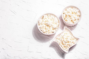 Seramik kasede süzme peynir. Derin bir tabakta ev yapımı süt ürünü. Beyaz macun arkaplan, üst görünüm