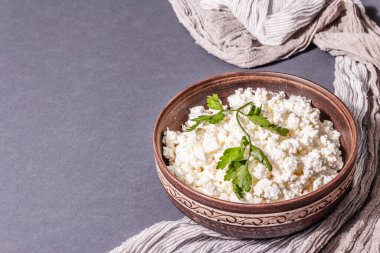 Seramik kasede içinde süt olan süzme peynir. Derin bir tabakta ev yapımı süt ürünü. Koyu gri arkaplan, metin için yer