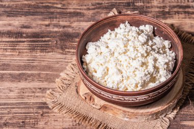 Seramik kasede süzme peynir. Derin bir tabakta ev yapımı süt ürünü. Eski ahşap masa, metin için yer