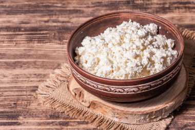 Seramik kasede süzme peynir. Derin bir tabakta ev yapımı süt ürünü. Eski ahşap masa, metin için yer