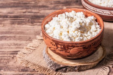 Seramik kasede süzme peynir. Derin bir tabakta ev yapımı süt ürünü. Eski ahşap masa, metin için yer