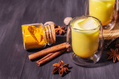 Buzlu altın zerdeçal sütü. Tarçın, hindistan cevizi, anason baharatları. Son moda sağlıklı içki konsepti. Modern bir sert ışık, karanlık gölge, siyah ahşap zemin, kopyalama alanı