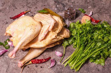 Sağlıklı bir yaşam tarzı için çiğ tavuk leşi. Maydanoz yeşili, sarımsak karanfili, baharat ve pişirme yağı ile serbest çiftlik kuşu. Modaya uygun bir sert ışık, koyu gölge, taş zemin, kopyalama alanı