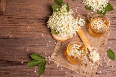 Mürver çiçeği çayı. Taze yaz içkisi, sağlıklı yaşam tarzı konsepti. Kumaş peçete, eski ahşap masa, üst manzara.