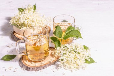 Mürver çiçeği çayı. Taze yaz içkisi, sağlıklı yaşam tarzı konsepti. Modaya uygun sert ışık, karanlık gölge. Eski beyaz tahta tahta arka plan, boşluğu kopyala