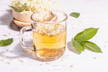 Mürver çiçeği çayı. Taze yaz içkisi, sağlıklı yaşam tarzı konsepti. Modaya uygun sert ışık, karanlık gölge. Eski beyaz tahta arka plan, kapat