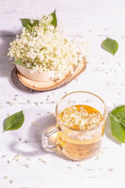 Mürver çiçeği çayı. Taze yaz içkisi, sağlıklı yaşam tarzı konsepti. Modaya uygun sert ışık, karanlık gölge. Eski beyaz tahta arka plan, kapat