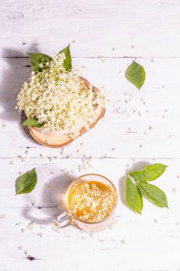 Mürver çiçeği çayı. Taze yaz içkisi, sağlıklı yaşam tarzı konsepti. Modaya uygun sert ışık, karanlık gölge. Eski beyaz tahta arka plan, üst görünüm
