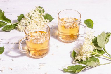 Mürver çiçeği çayı. Taze yaz içkisi, sağlıklı yaşam tarzı konsepti. Modaya uygun sert ışık, karanlık gölge. Eski beyaz tahta arka plan, kapat