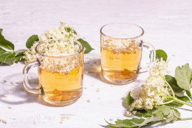 Mürver çiçeği çayı. Taze yaz içkisi, sağlıklı yaşam tarzı konsepti. Modaya uygun sert ışık, karanlık gölge. Eski beyaz tahta tahta arka plan, boşluğu kopyala