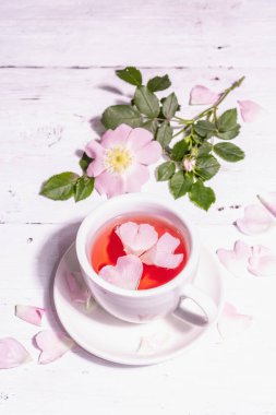 Gül kalça çiçekleri çayı. Yaz vitamini içeceği, sert ışık, karanlık gölge. Beyaz tahta arkaplan, boşluğu kopyala