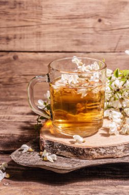 Akasya çiçeklerinden çay. Sağlıklı yaz vitamin içeceği, sert ışık, karanlık gölge. Tatlı bal, eski ahşap stantlar, kopyalama alanı