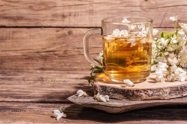 Akasya çiçeklerinden çay. Sağlıklı yaz vitamin içeceği, sert ışık, karanlık gölge. Tatlı bal, eski ahşap stantlar, kopyalama alanı